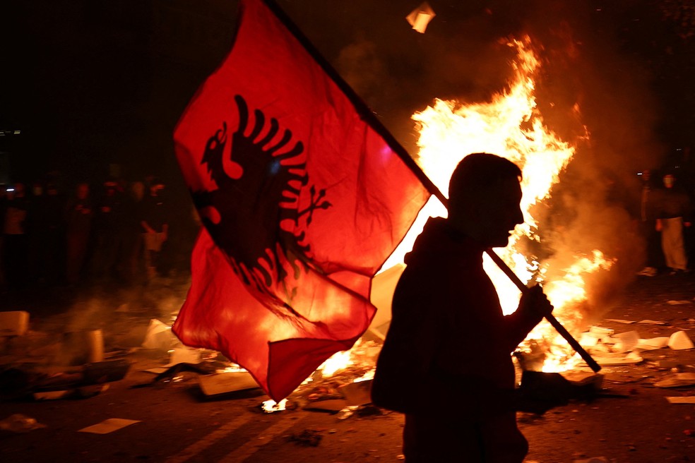 Manifestante segura uma bandeira nacional da Albânia enquanto estudantes albaneses realizam um protesto antigovernamental em Tirana — Foto: REUTERS/Florion Goga