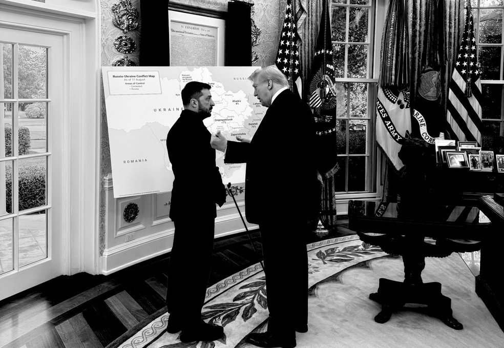 Presidentes dos Estados Unidos, Donald Trump, e da Ucrânia, Volodymyr Zelensky, conversam diante de um mapa da Ucrânia com regiões ocupadas pela Rússia marcadas por cor diferente, em 18 de agosto de 2025. — Foto: Divulgação/ Casa Branca