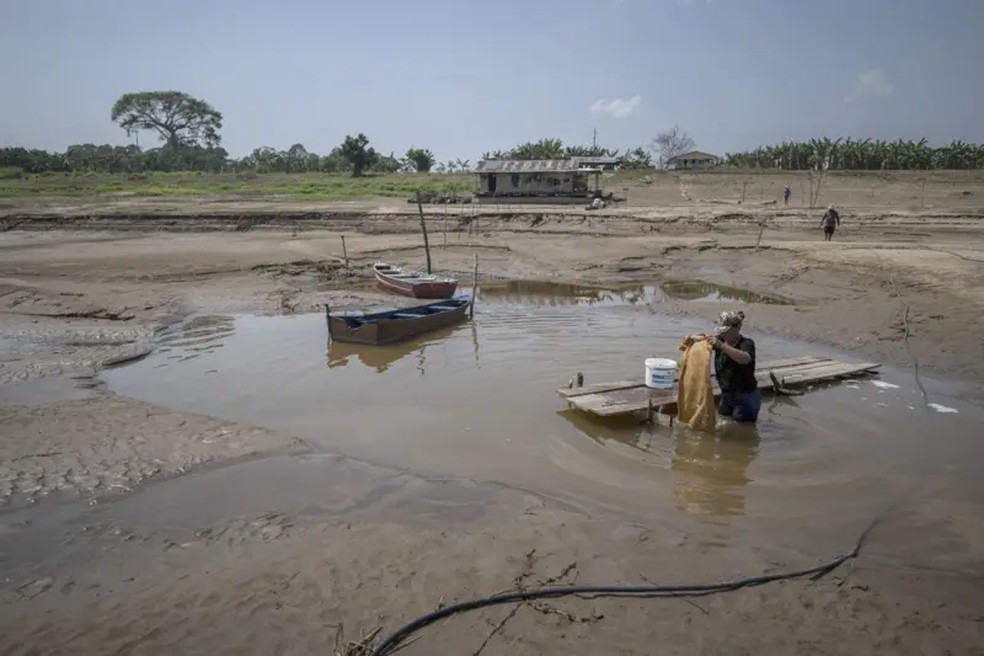 Mulher lava roupas em uma poça no que sobrou de água do rio Costa do Barroso, em Manaquiri, Amazonas. — Foto: Raphael Alves/EPA-EFE/REX/Shutterstock