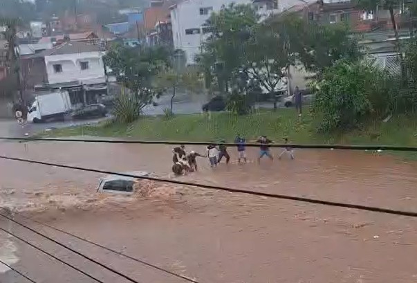 VÍDEO: Mulher fica presa dentro de carro em enchente e é resgatada por vizinhos em Itapecerica da Serra, na Grande SP