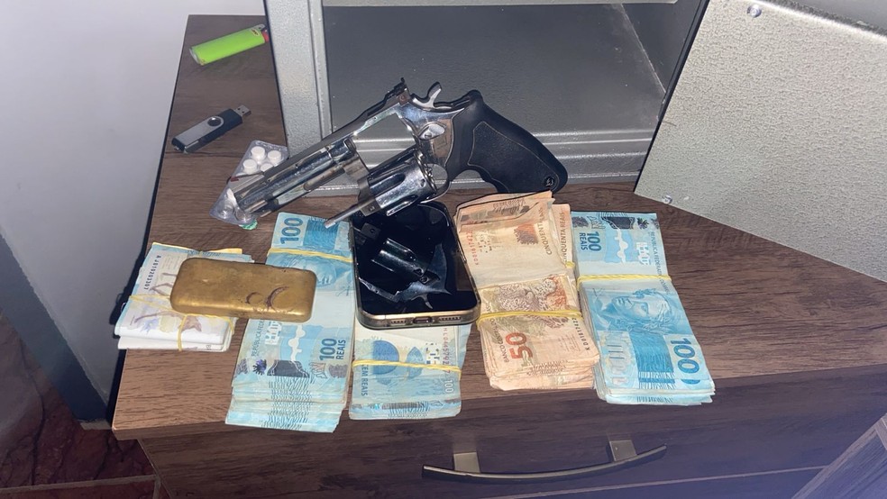 Arma, barra de ouro, celular e dinheiro apreendidos com alvos da operação — Foto: Polícia Civil