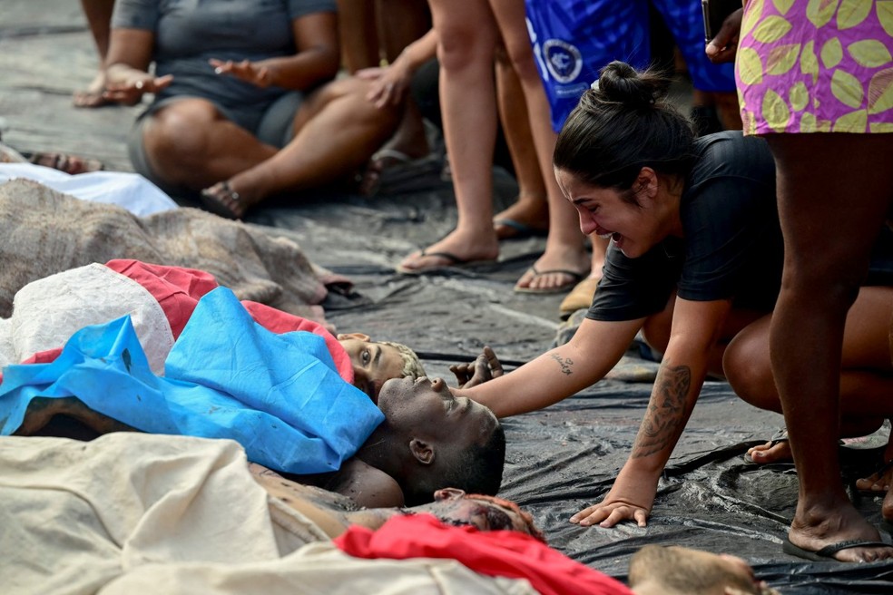 Mulher chora ao lado de corpo de morto durante megaoperação no Rio; corpos foram estendidos na Praça São Lucas, na favela Vila Cruzeiro, no Complexo da Penha, no Rio de Janeiro, Brasil, em 29 de outubro de 2025. — Foto: Pablo Porciuncula/AFP