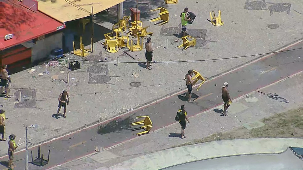 Torcedores do Peñarol usam mesas como escudo em confronto na orla do Recreio dos Bandeirantes — Foto: Reprodução/ TV Globo