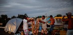 Homens dobram um cobertor enquanto acampam na estrada perto de uma rua inundada em Eldorado do Sul, no Rio Grande do Sul, Brasil, 6 de maio de 2024. — Foto: Reuters/Amanda Perobelli