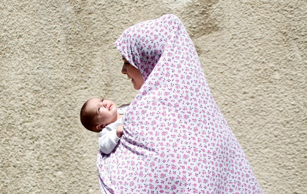 Uma mulher palestina carrega um bebê após ataque aéreo de Israel em Gaza, em 11 de maio de 2021 — Foto: Mohammed Salem /Reuters