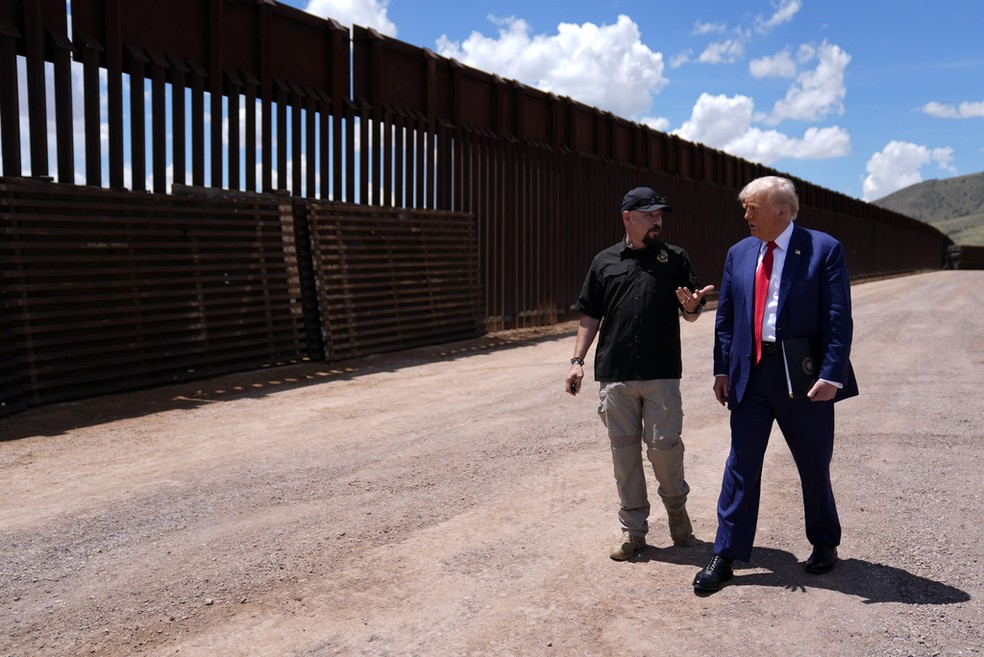 Donald Trump caminha ao lado de muro que demarca a fronteira dos EUA com o México, no Arizona, em agosto de 2024 — Foto: Evan Vucci/AP Photo
