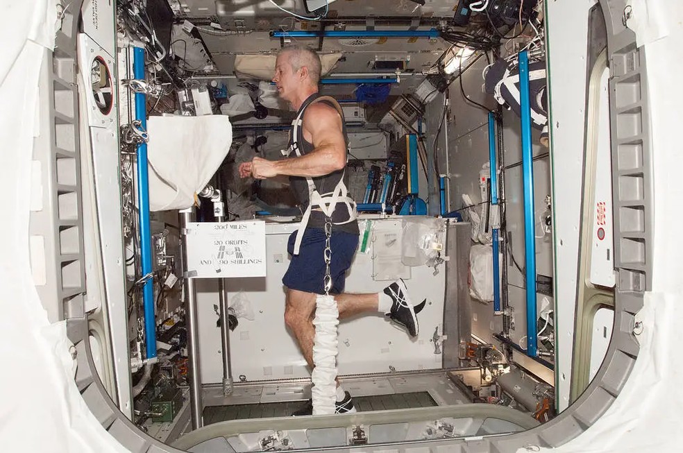O astronauta da Nasa Steve Swanson é visto correndo preso por elásticos na esteira da estação. — Foto: NASA