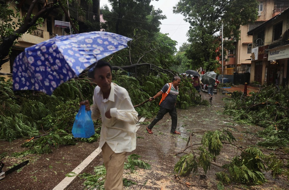 Um trabalhador remove árvores caídas após fortes chuvas em Mumbai, Índia. — Foto: Francis Mascarenhas /Reuters