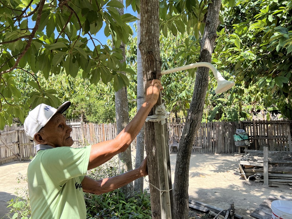 José Costa Reis, 87 anos, abrindo um chuveiro no quintal da casa em Mucajaí, Sul de Roraima — Foto: Caíque Rodrigues/g1 RR