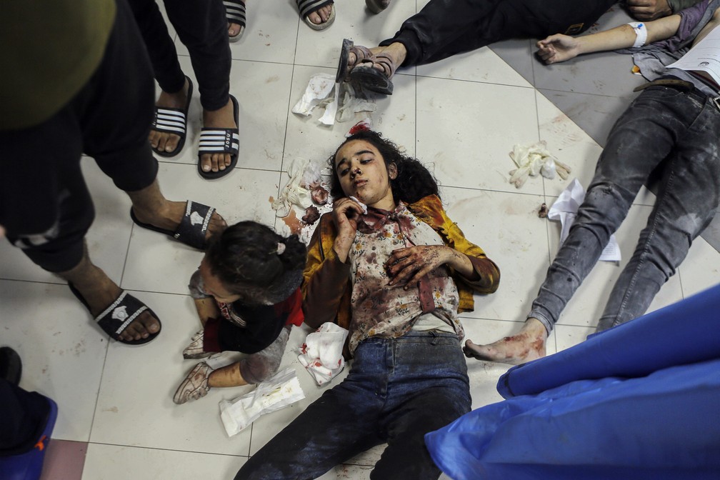Menina palestina aguarda por atendimento deitada no chão do hospital Al Shifa, após ataque que deixou centenas de mortos nesta terça-feira (17) no hospital Al Ahly, ambos na Cidade de Gaza — Foto: Abed Khaled/AP