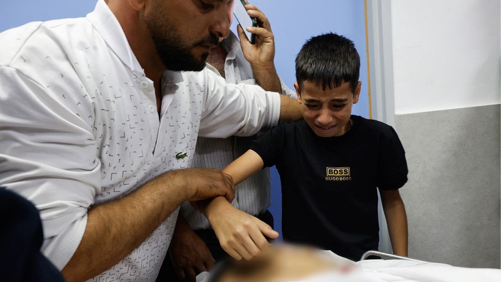 Menino perto do corpo de Yousef Idrees, um palestino que foi morto em confrontos — Foto: Reuters