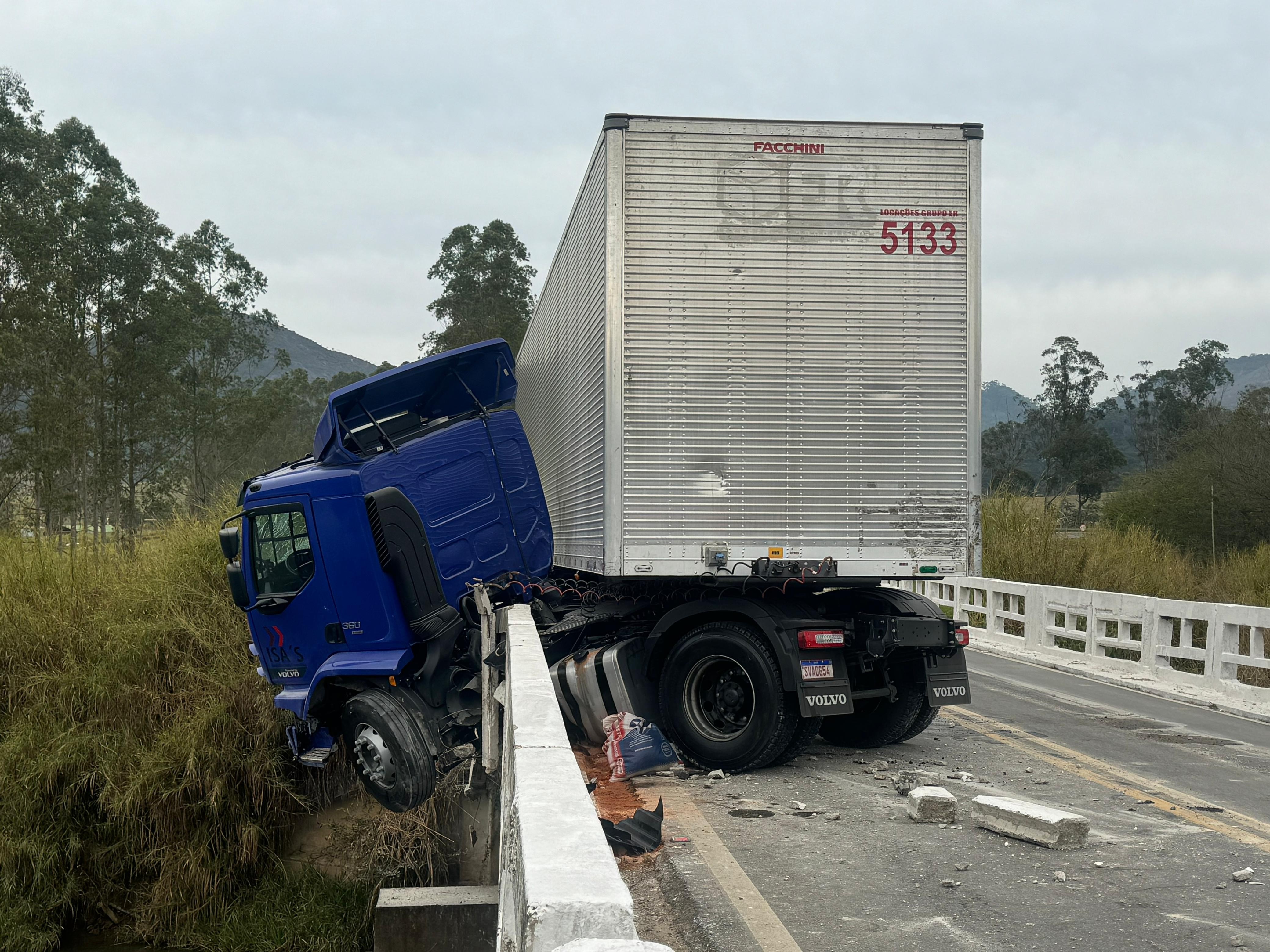 Carreta com 6 toneladas de mercadorias fica pendurada em ponte na BR-267 e motorista se salva