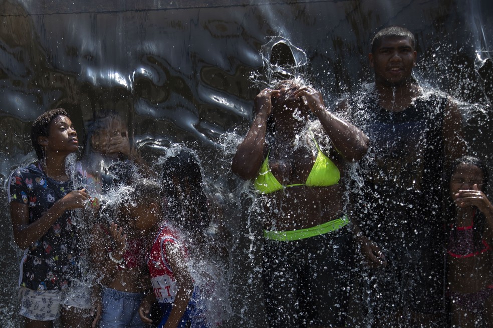  Pessoas se refrescam em fonte de água no Parque Madureira, no Rio de Janeiro, em meio a uma onda de calor que tomou boa parte do território nacional — Foto: Bruna Prado/AP