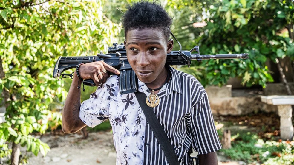 Um jovem membro de gangue de 14 anos patrulha as ruas do bairro Mariani de Porto Príncipe, no Haiti, no dia 6 de outubro de 2025 — Foto: Clarens Siffroy via BBC