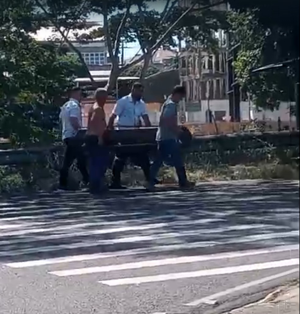 Homens recolocaram o caixão no carro funerário — Foto: Redes sociais