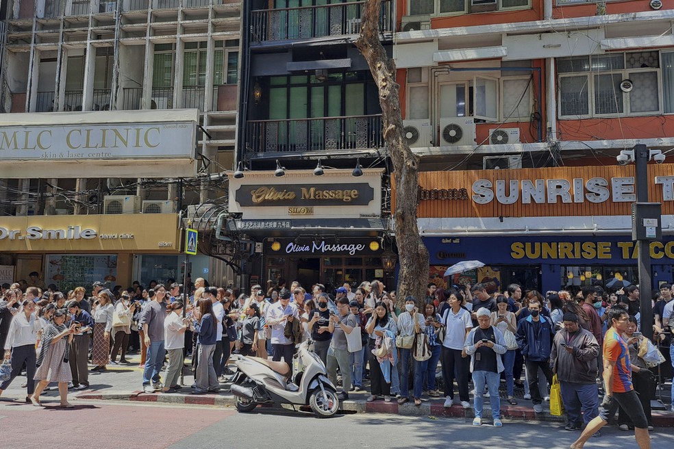 Pessoas aguardam nas ruas de Bangkok após prédio ser evacuado. — Foto: Chutima Lalit/AP Photo