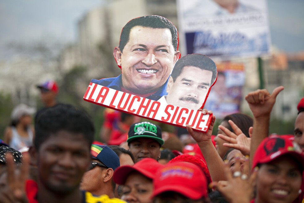 Cartaz com as fotos de Hugo Chávez e Nicolás Maduro, em abril de 2013 — Foto: Ramon Espinosa/AP