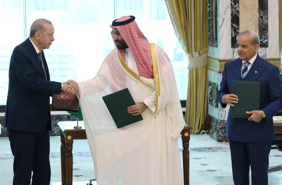 O presidente turco, Recep Tayyip Erdogan (à esq.), o príncipe herdeiro saudita, Mohammed bin Salman (ao centro), é o primeiro-ministro do Paquistão, Shehbaz Sharif, durante assinatura de pacto de defesa entre os dois países, em Meca, na Arábia Saudita, em 7 de agosto de 2026. — Foto: Murat Cetinmuhurdar/Turkish Presidential Press Office