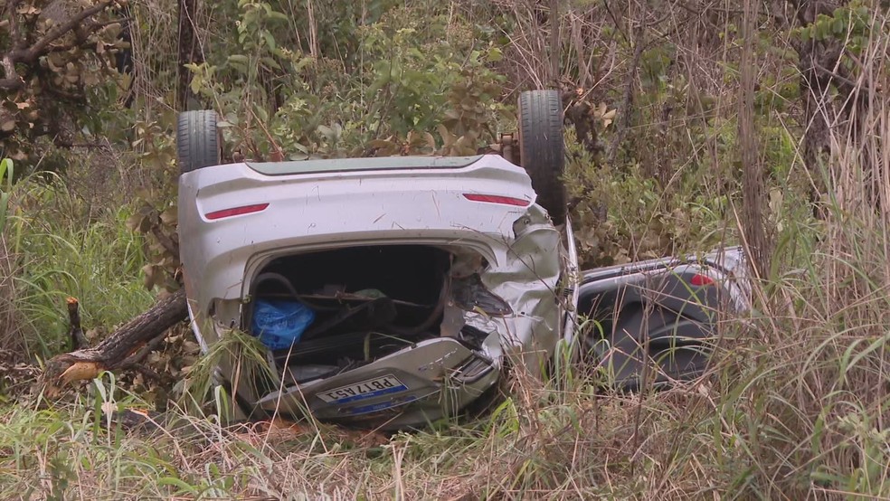 Após atropelar ciclista, carro bateu em uma árvore, capotou e parou com as quatro rodas para cima fora da pista. — Foto: TV Globo/Reprodução