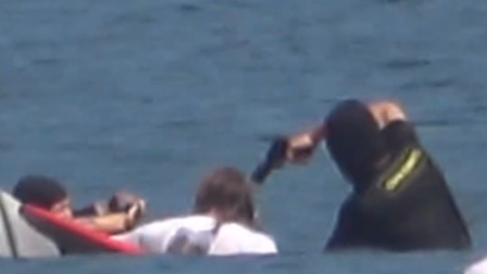 É #FAKE que foto mostre surfista sendo assaltado dentro do mar no Rio; cena é 'pegadinha' na Indonésia - Cena foi gravada em Bali e mostra encenação de prisão de surfista no mar. Ao Fato ou Fake, PM do Rio disse jamais ter sido acionado para caso como o mencionado no post viral.