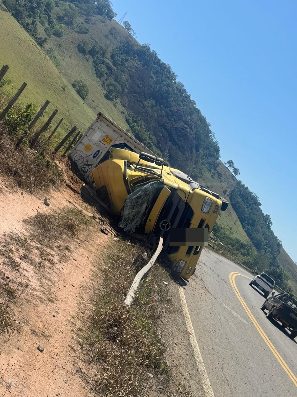 Carreta com contêiner tomba e motorista morre preso às ferragens na MG-133