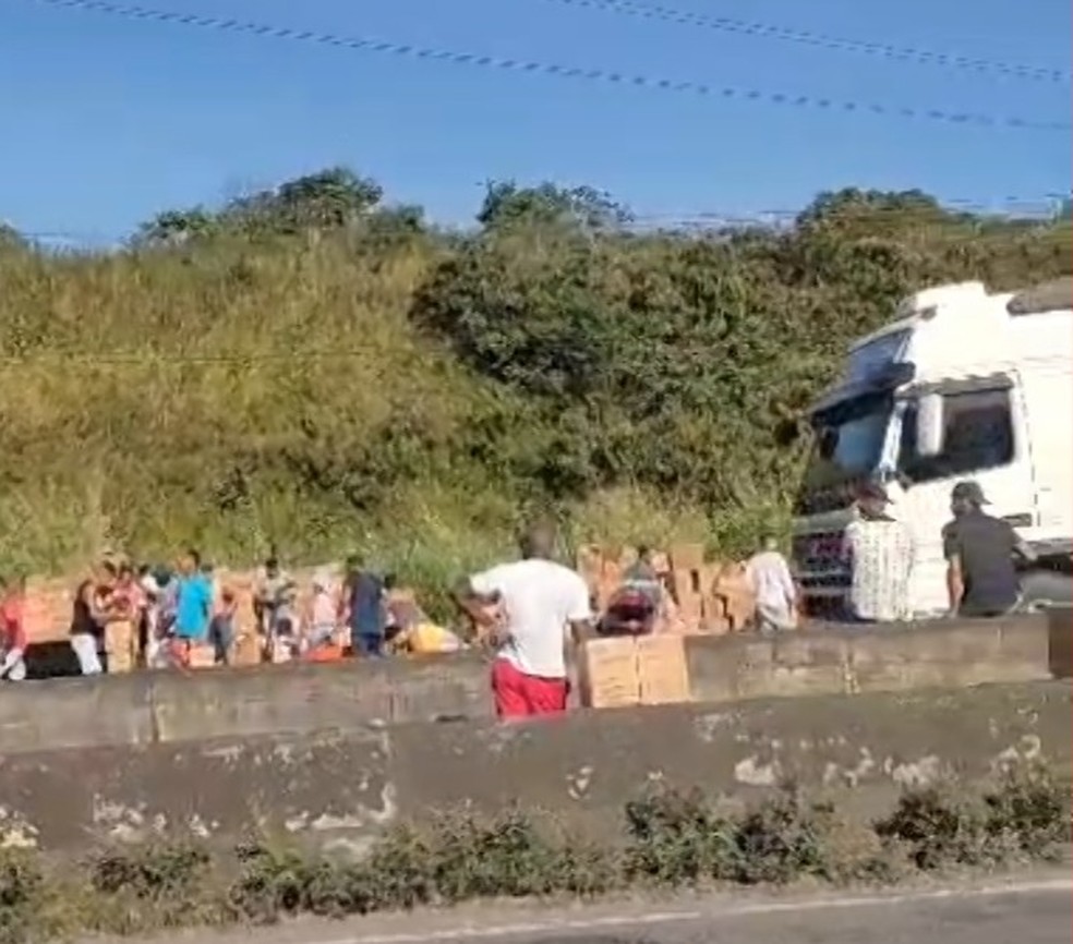 Caminhão carregado de biscoitos tomba na BR-324 e parte da carga é saqueada — Foto: Reprodução/TV Bahia