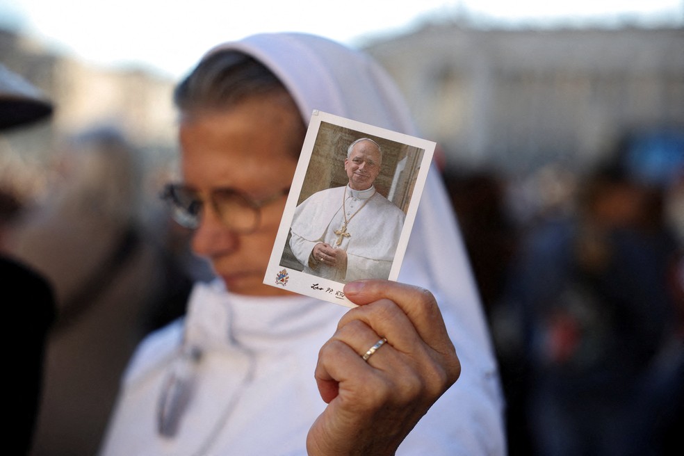 Freira segura foto do papa Leão XIV durante missa na Praça de São Pedro, no Vaticano, em 14 de outubro de 2026. — Foto: REUTERS/Stoyan Nenov