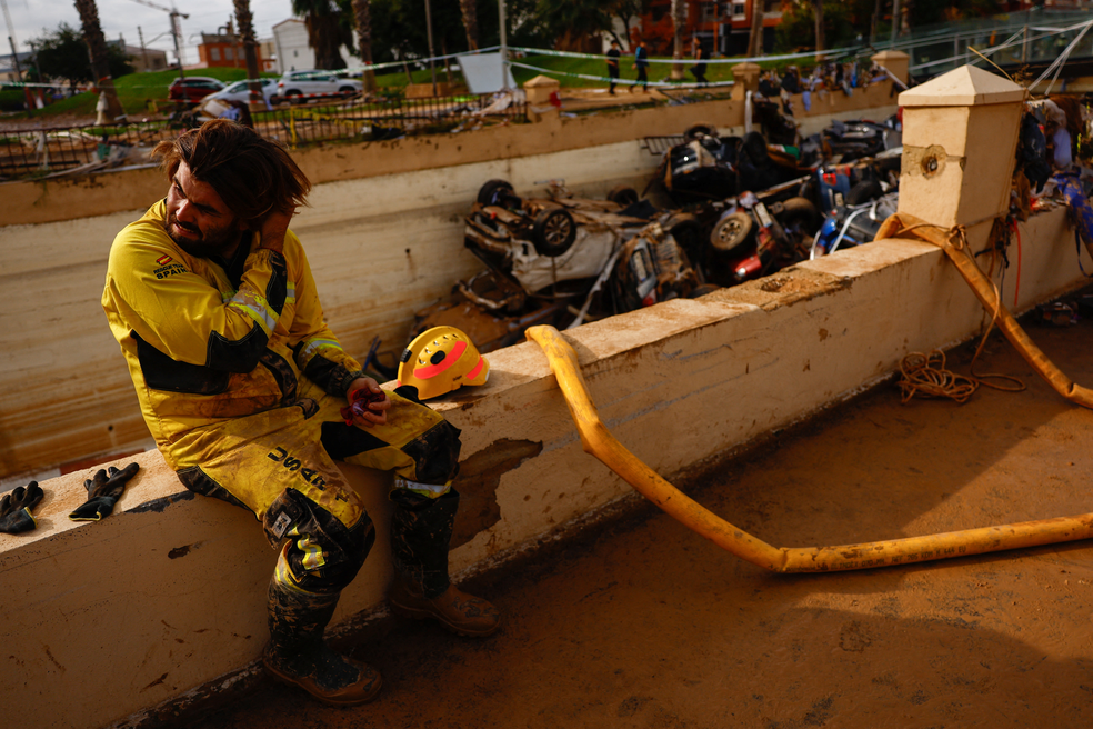 Bombeiro descansa diante de pilha de carros que ficaram presos na entrada de um túnel em Valência, na Espanha, durante uma enchente história na região, em 1º de novembro de 2024. — Foto: Susana Vera/ Reuters