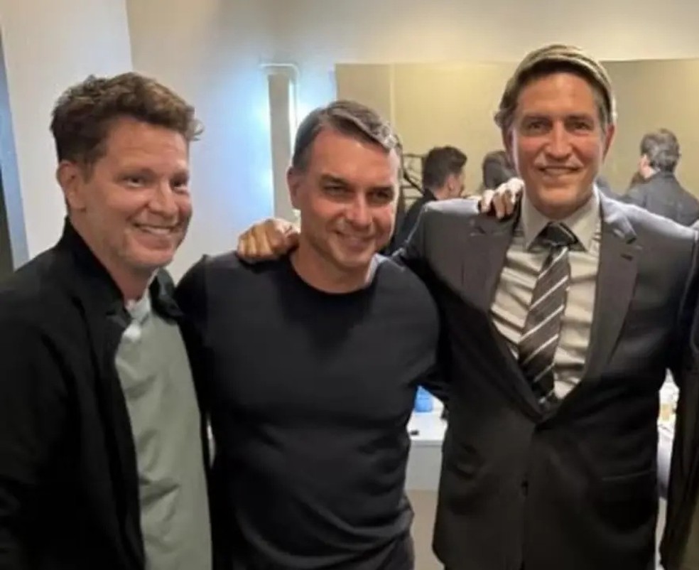 O deputado M�rio Frias, o senador Fl�vio  Bolsonaro e o ator Jim Caviezel, que interpreta o ex-presidente Jair Bolsonaro no filme 'Dark Horse' (O Azar�o), sobre a vida do ex-presidente brasileiro. � Foto: Reprodu��o/Redes Sociais