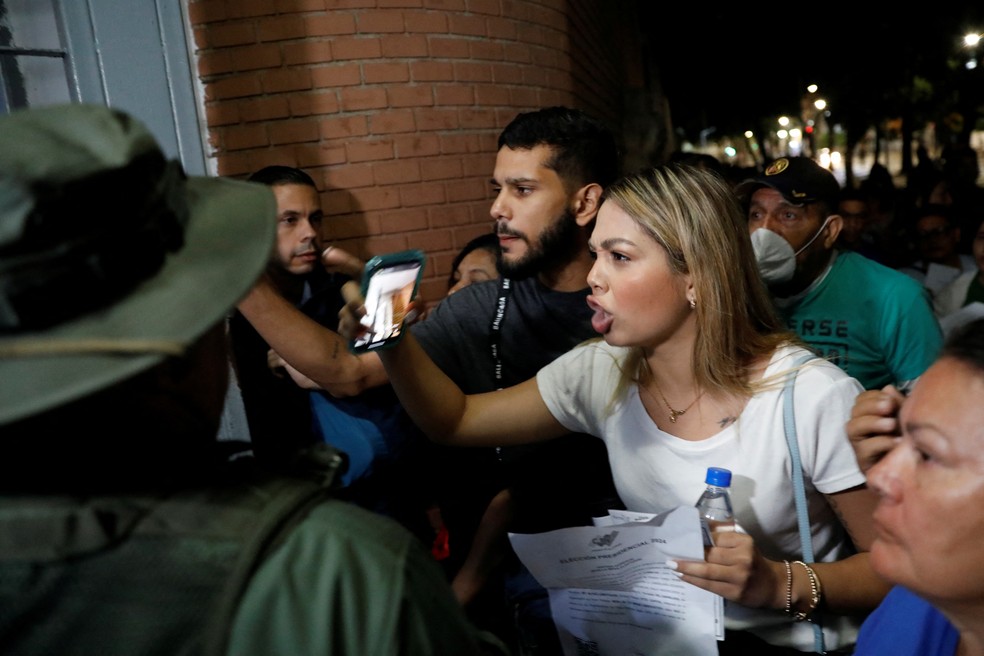 Voluntários dos partidos de oposição e pró-governo enfrentam a segurança exigindo entrar no centro eleitoral Andrés Bello, em Caracas, Venezuela, 28 de julho de 2024 — Foto: Reuters/Leonardo Fernandez Viloria