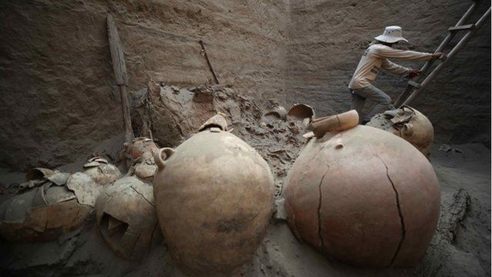 Objetos com tom de terra, e arqueólogo ao fundo subindo escada — Foto: EPA/via BBC