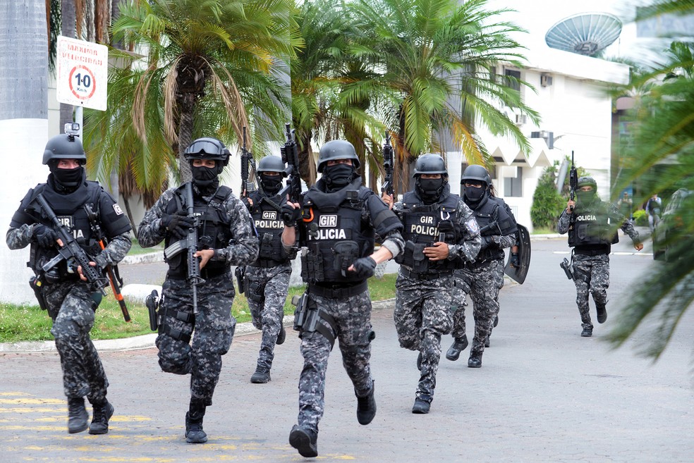 Policiais correm do lado de fora dos estúdios da televisão estatal TC após a invasão de uma transmissão ao vivo por homens armados em Guaiaquil, no Equador — Foto: Stringer via AFP
