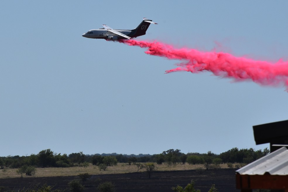 Um avião-tanque despeja retardante de fogo em um campo após queda de helicóptero militar dos EUA — Foto: Brent Johnson/The Killeen Daily Herald via AP