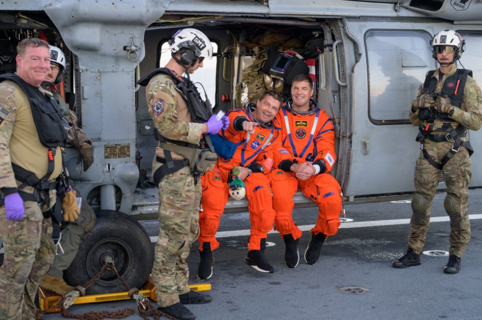 O astronauta da NASA Reid Wiseman, comandante da Artemis II, à esquerda, e o astronauta da CSA (Agência Espacial Canadense) Jeremy Hansen, especialista da missão Artemis II, são vistos sentados em um helicóptero MH-60 Seahawk da Marinha, do Esquadrão de Combate Marítimo de Helicópteros (HSC) 23, no convés de voo do USS John P. Murtha, — Foto: NASA/Bill Ingalls