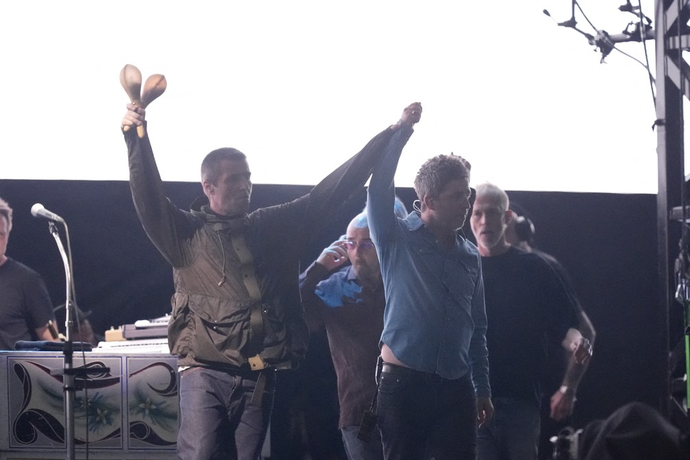 Liam Gallagher e Noel Gallagher durante o show do retorno do Oasis, em Cardiff, em 4 de julho de 2025 — Foto: AFP stringer / AFP